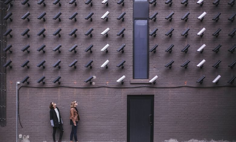 two women standing in front of a wall of cameras