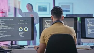 a man sitting at a desk with two monitors